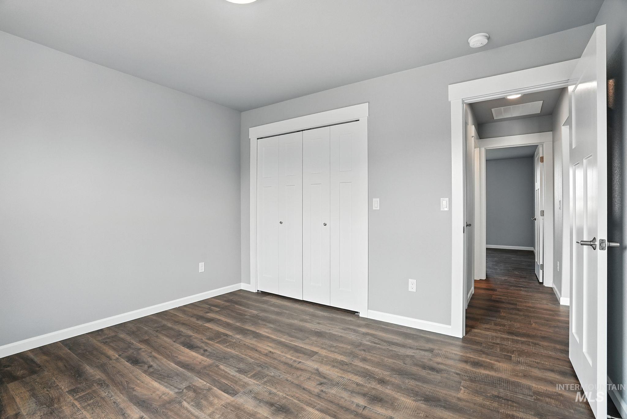 Unfurnished bedroom with dark wood-style flooring and a closet