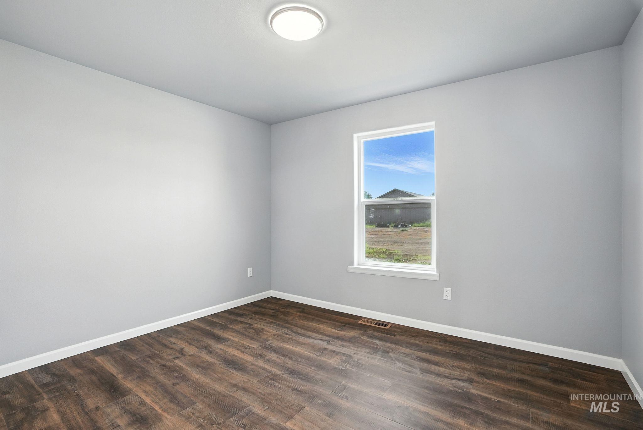 Unfurnished room with baseboards and dark wood finished floors