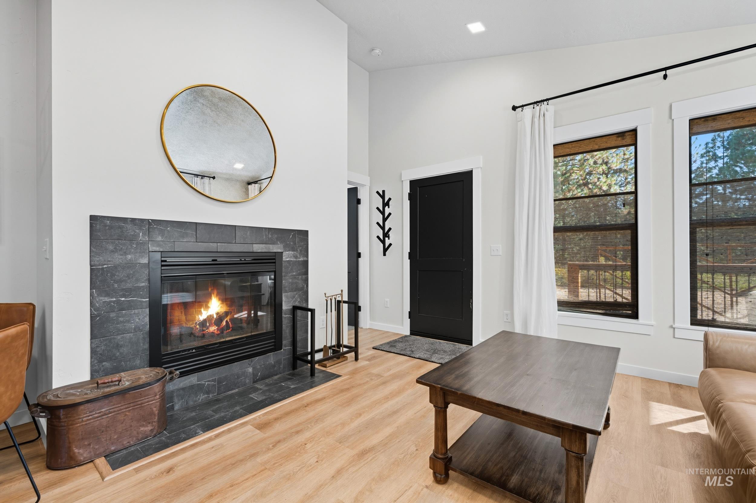 Living area with vaulted ceiling, a fireplace, light wood finished floors, and recessed lighting
