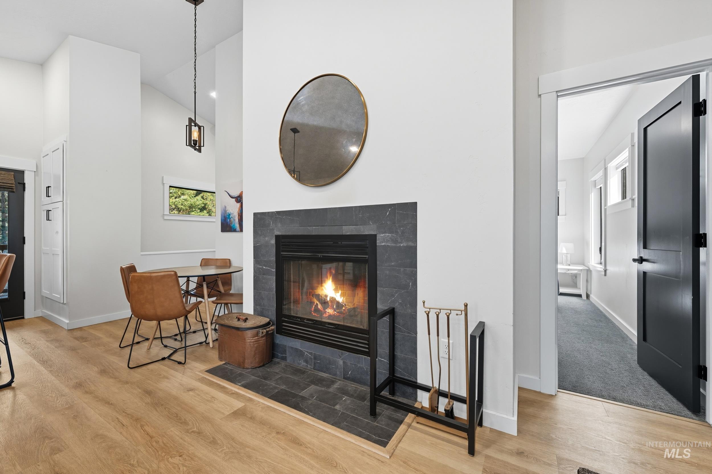 Living room featuring high vaulted ceiling, a tiled fireplace, and light wood-type flooring