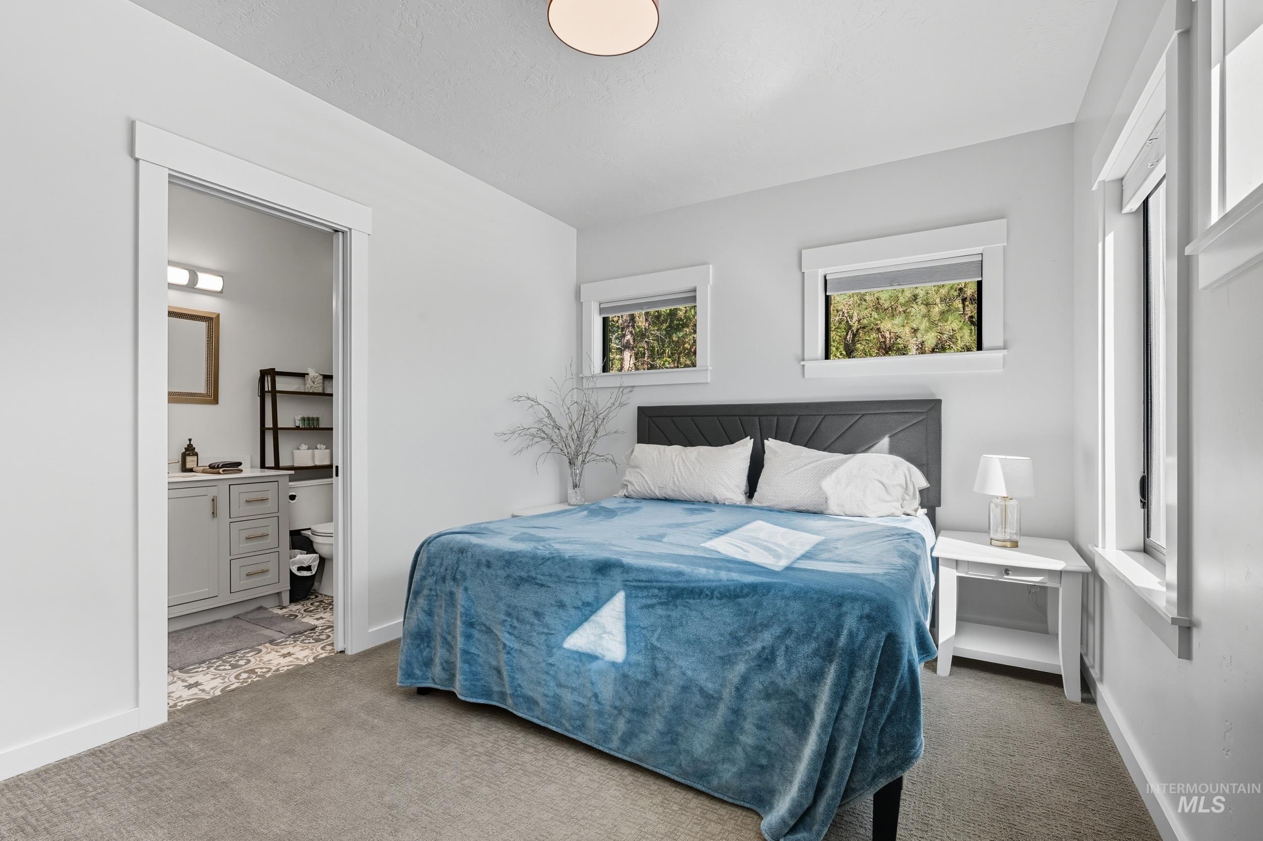 Carpeted bedroom featuring baseboards and ensuite bathroom