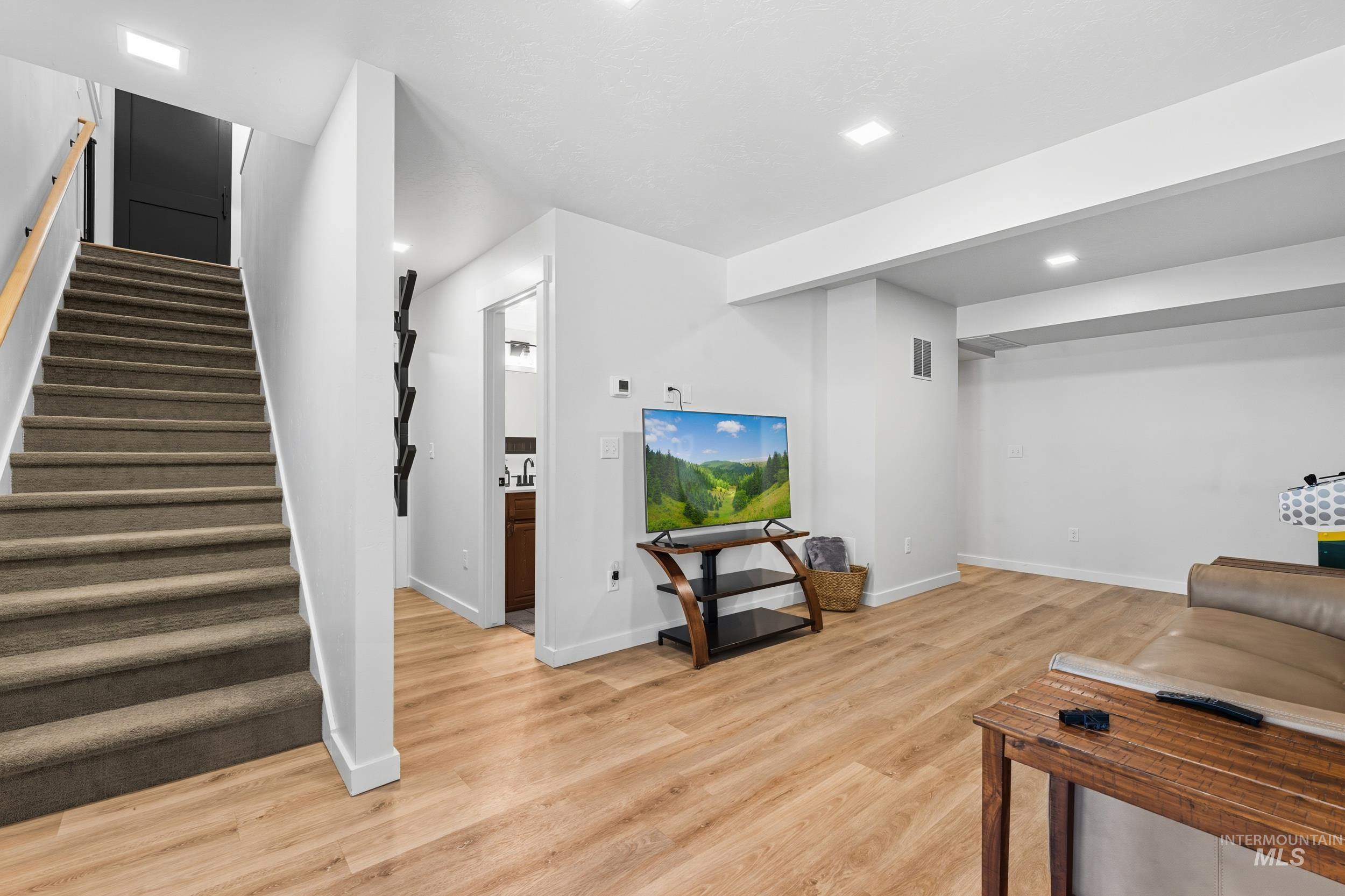 Living room featuring recessed lighting, stairs, and light wood-style flooring