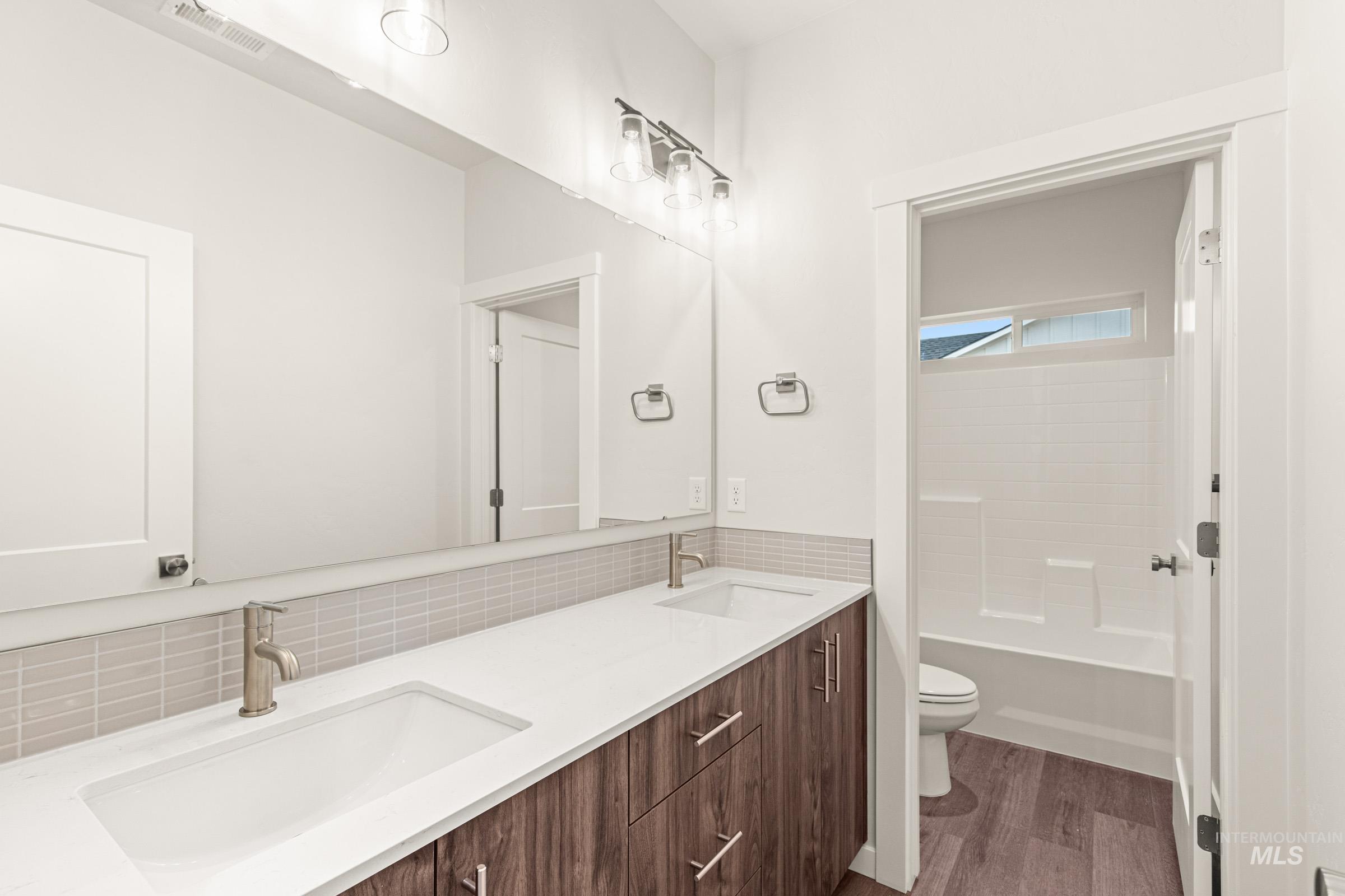 Bathroom featuring a dual-sink vanity with a white countertop, wood-finish cabinetry, and brushed nickel fixtures