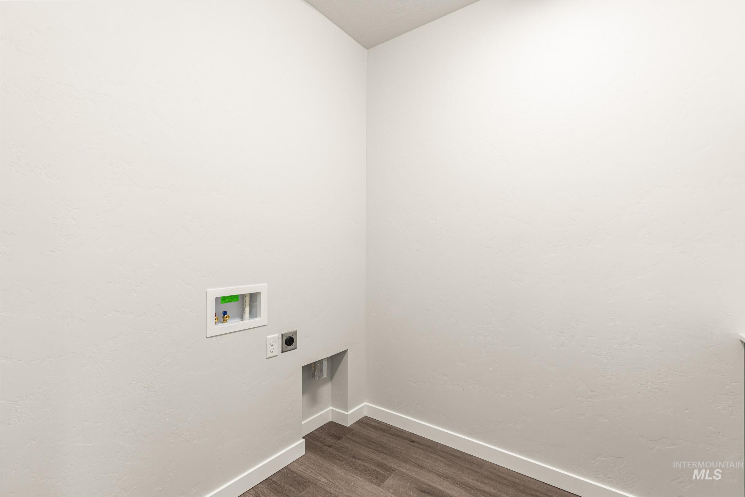 Laundry area featuring wood-finish flooring, white baseboards, and a dedicated utility box