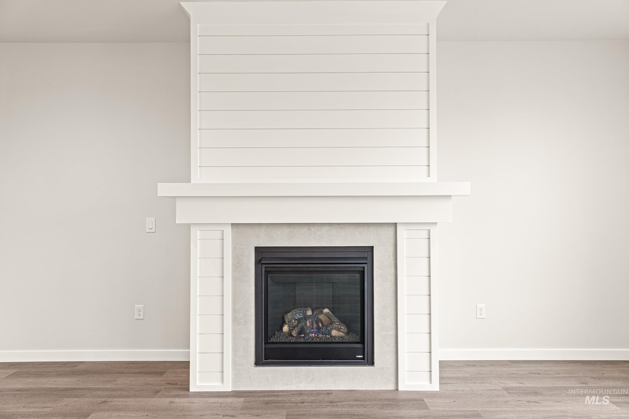 Modern fireplace featuring a white shiplap surround, mantel, and tiled hearth