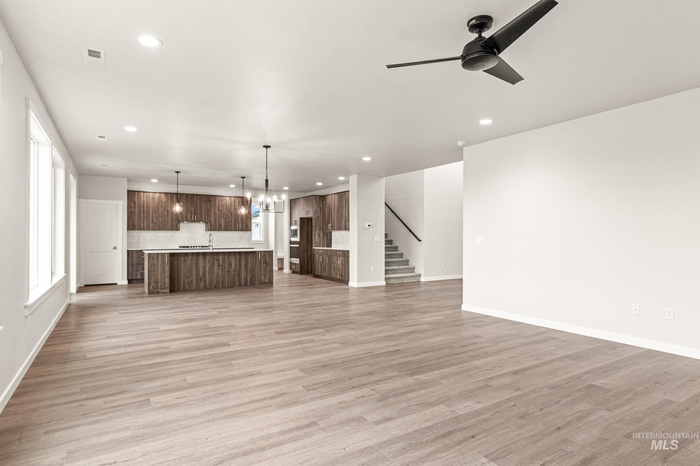 Open-concept living area with wood-finish flooring, recessed lighting, and a modern ceiling fan