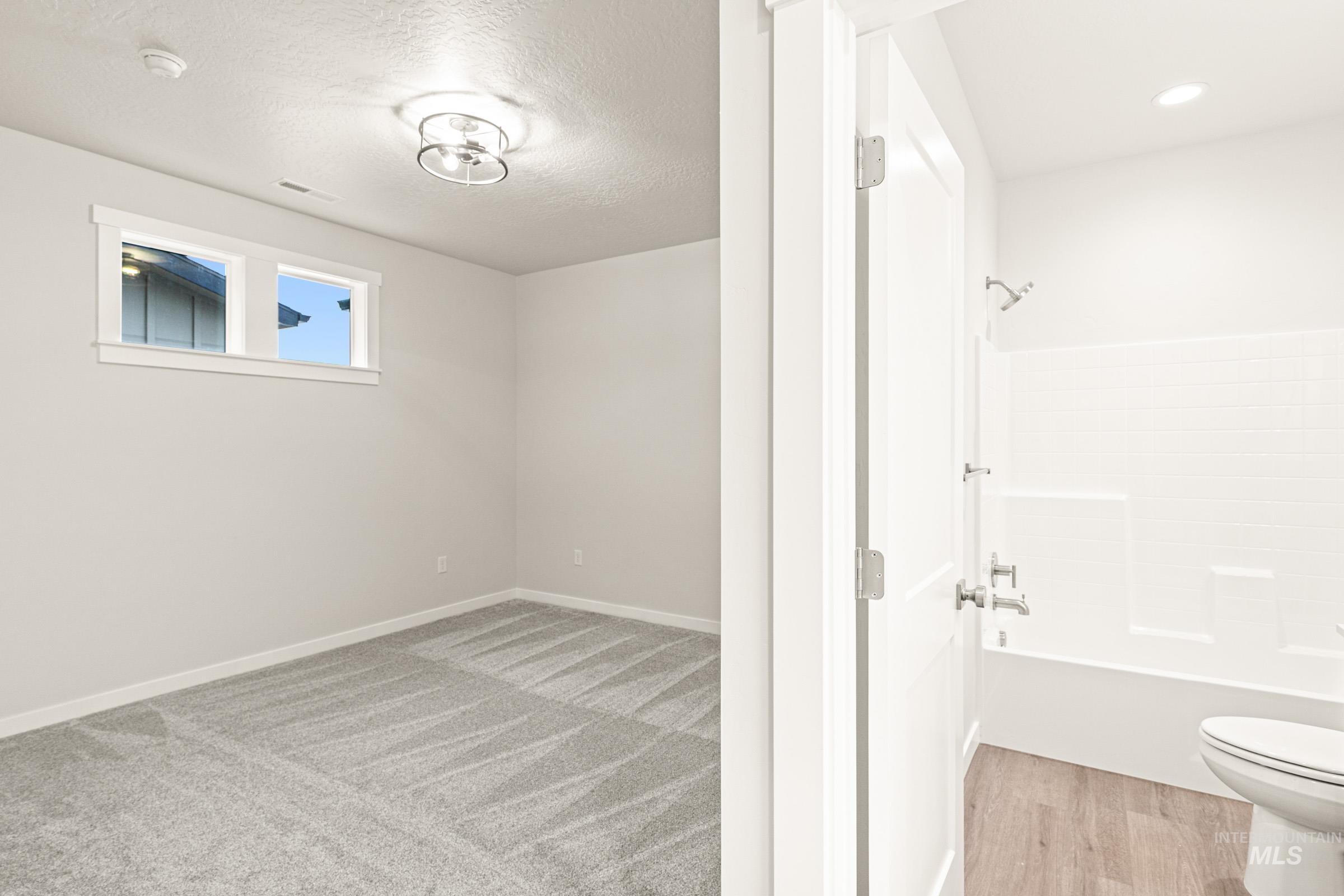 Bright interior room with textured gray carpet, featuring a flush mount ceiling light fixture and two windows
