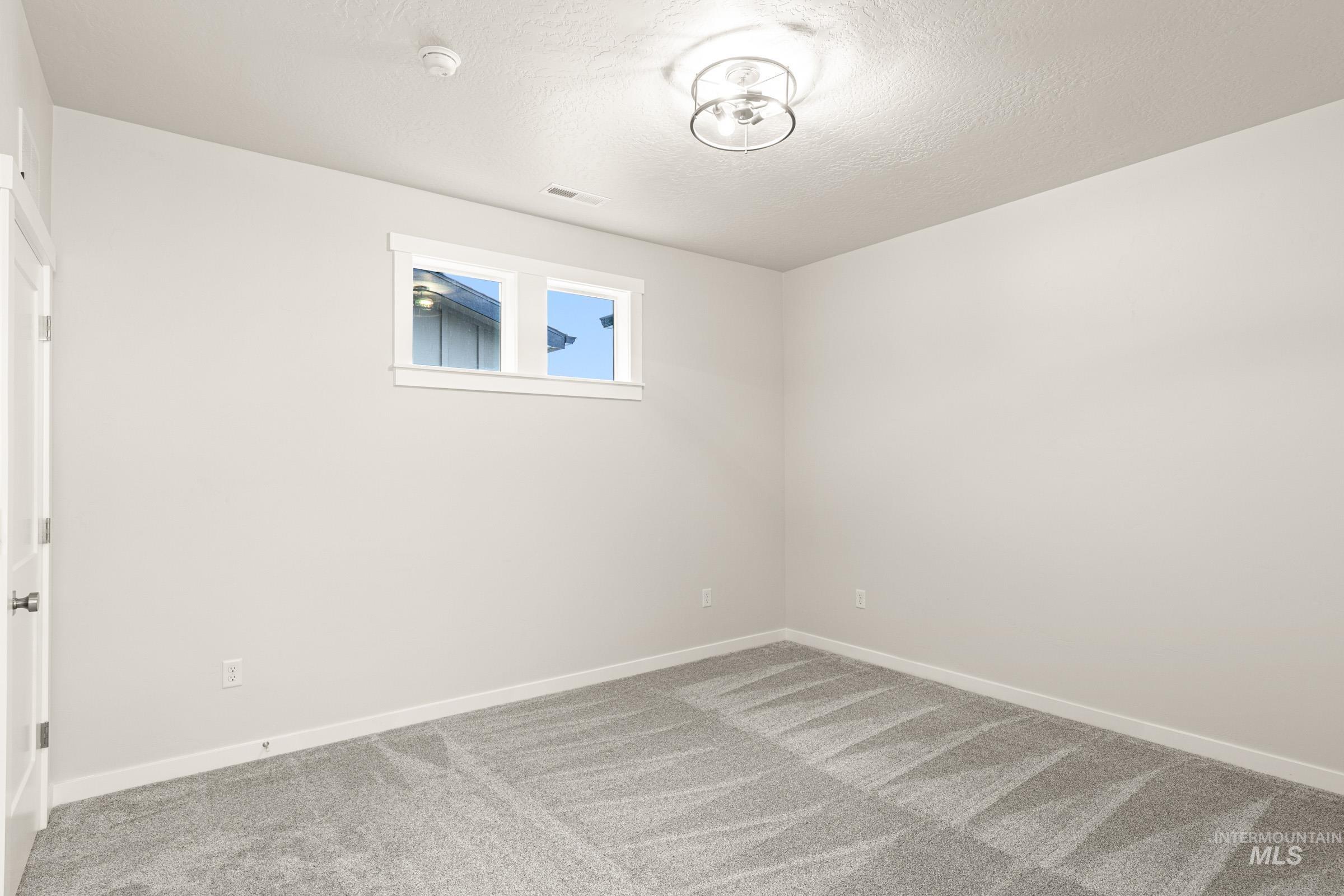Light gray carpeting with a patterned finish, neutral wall paint, and a modern semi-flush mount ceiling light fixture