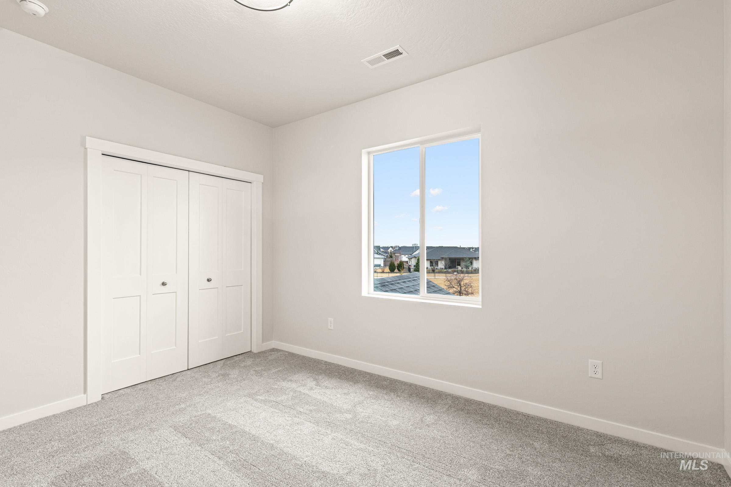 Bedroom featuring light gray walls, gray carpeting, a single window, and white bi-fold closet doors
