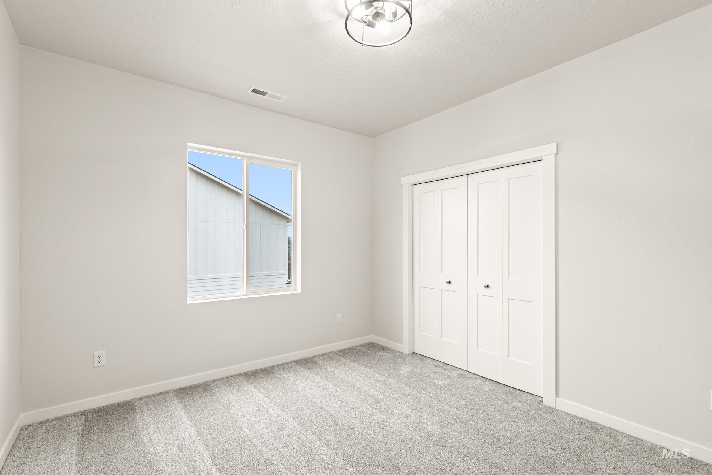Neutral wall paint, light gray patterned carpeting, and white trim