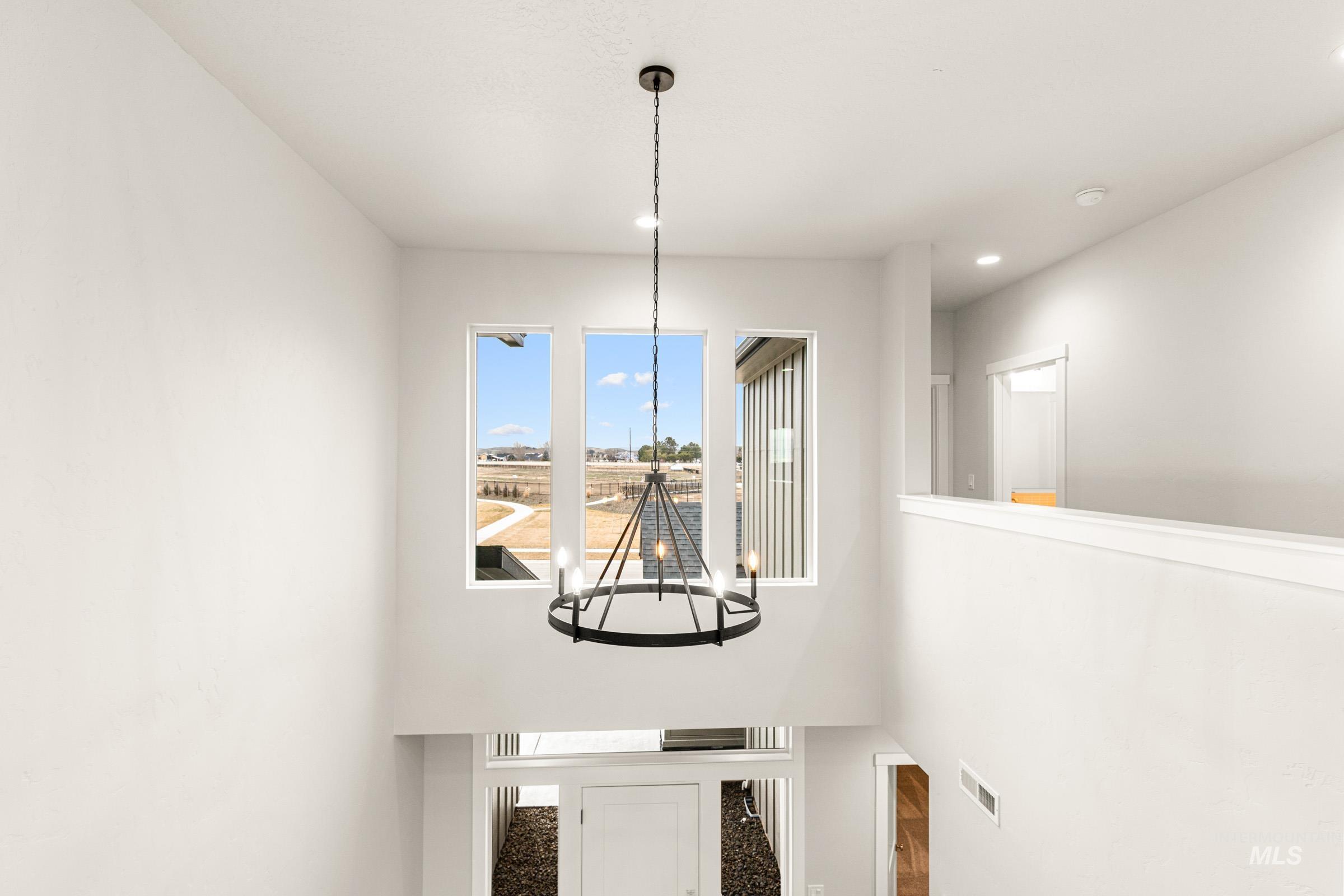 Two-story entryway with a modern chandelier and a trio of tall windows