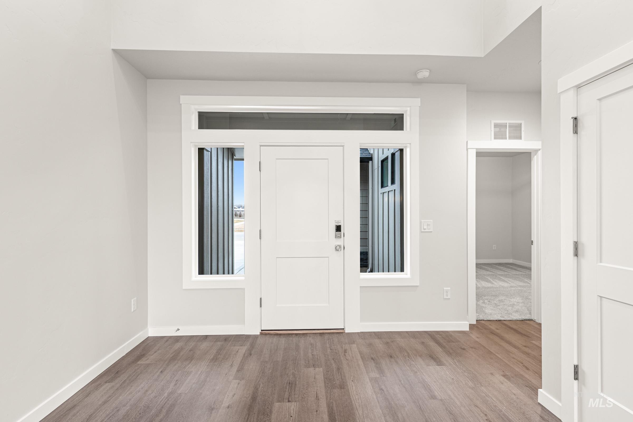 Entryway featuring wood-finish flooring, a white paneled door with sidelights and transom window, and a recessed ceiling light