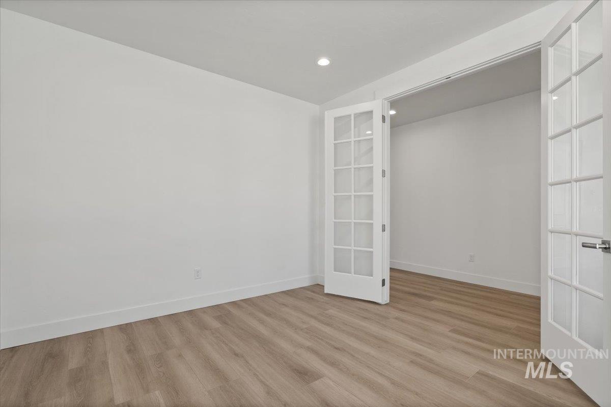 Empty room featuring light wood-type flooring, recessed lighting, and french doors