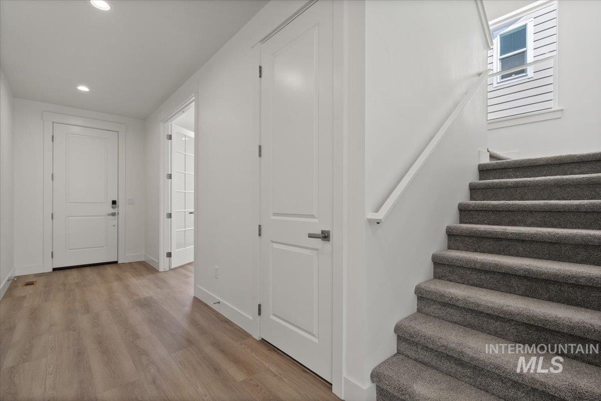 Stairway featuring wood finished floors and recessed lighting