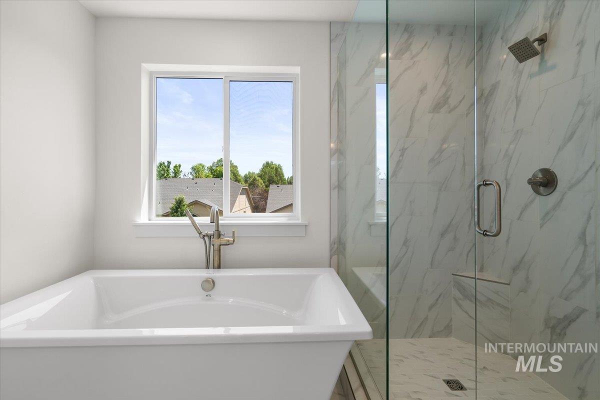Bathroom featuring a marble finish shower and a freestanding bath