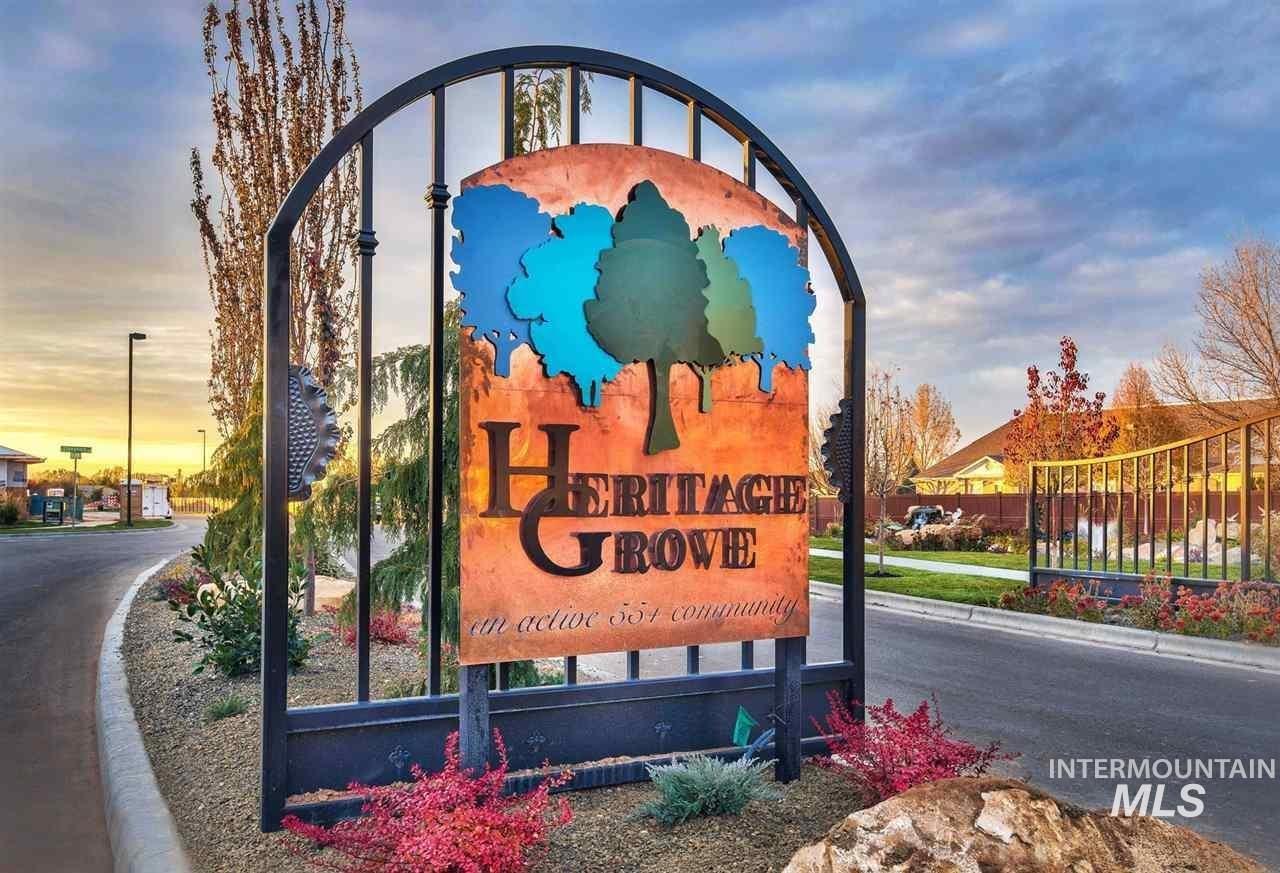 Wrought iron entry gate featuring a prominent community sign, adjacent to a paved road with landscaped borders