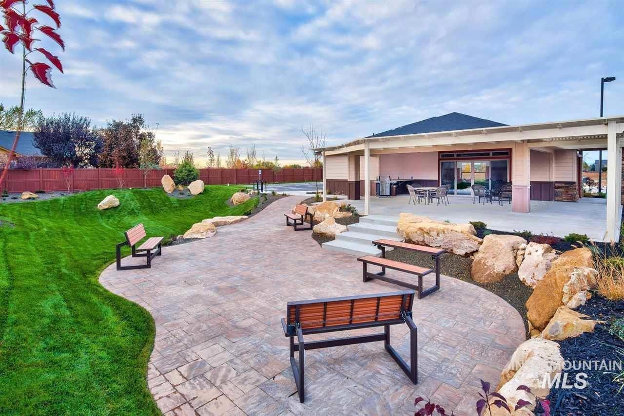 Outdoor amenity space featuring a covered patio, paved walkway, and tiered grassy areas