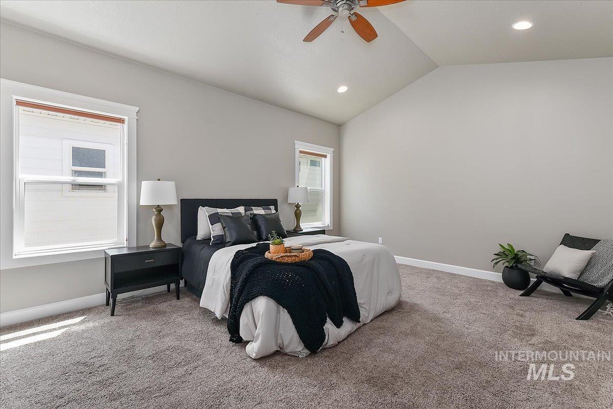 Spacious bedroom featuring vaulted ceilings, recessed lighting, and a ceiling fan