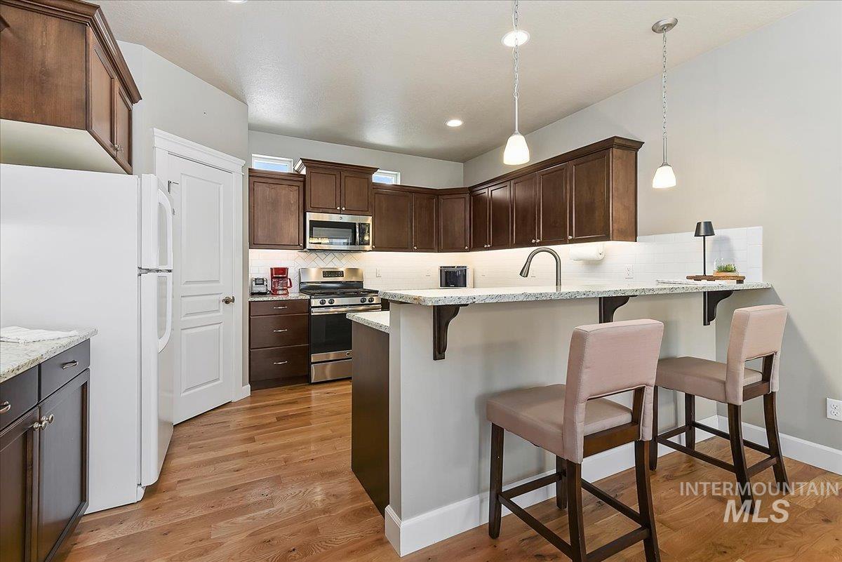 Kitchen featuring wood-finish flooring, dark wood cabinetry, white countertops, and stainless steel appliances