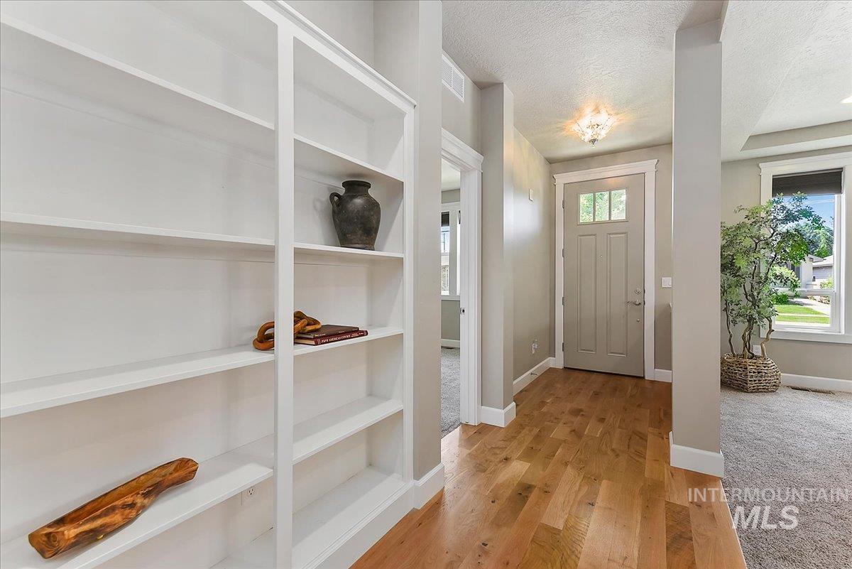 Entryway featuring light wood-finish flooring, a paneled door with glass inserts, and a decorative ceiling light fixture