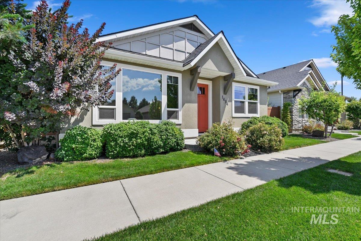 Contemporary single-story residence featuring a stucco exterior with gabled roofing and a vibrant red entry door