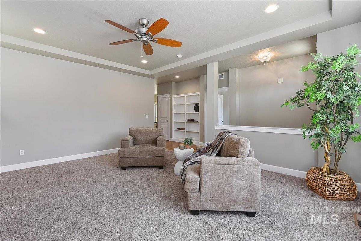 Carpeted living area featuring a ceiling fan with integrated lighting, recessed lighting, and crown molding