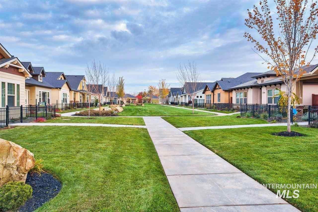 Community green space featuring expansive lawns, mature trees, and concrete walkways