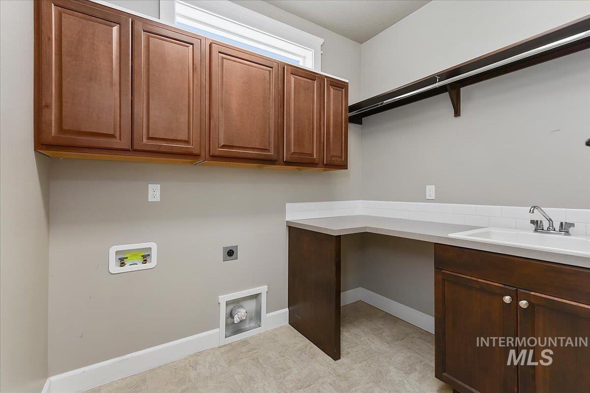 Laundry room featuring upper and lower cabinetry, a utility sink, and a built-in countertop workspace