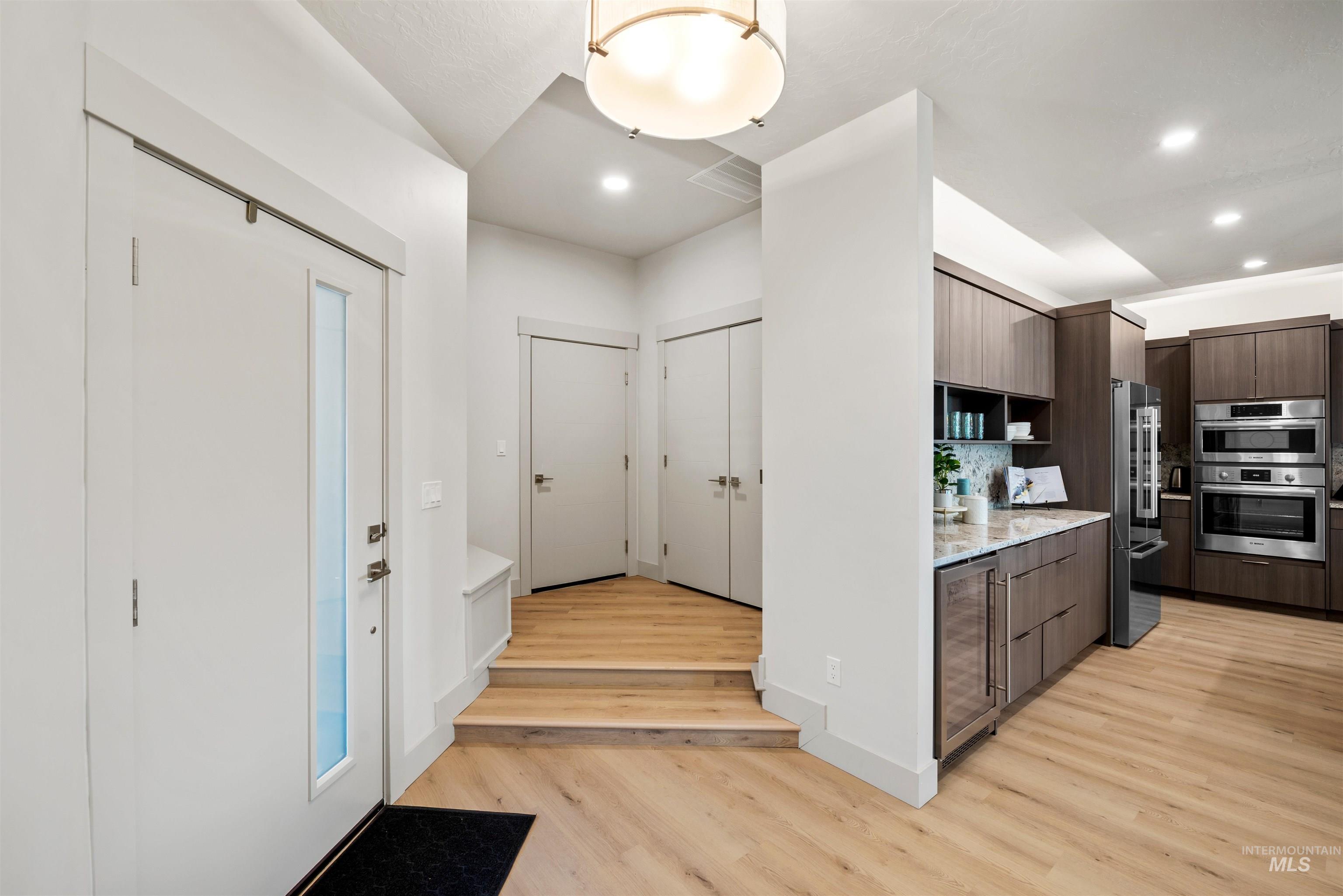 Kitchen featuring modern cabinets, light wood-type flooring, backsplash, light stone countertops, and recessed lighting