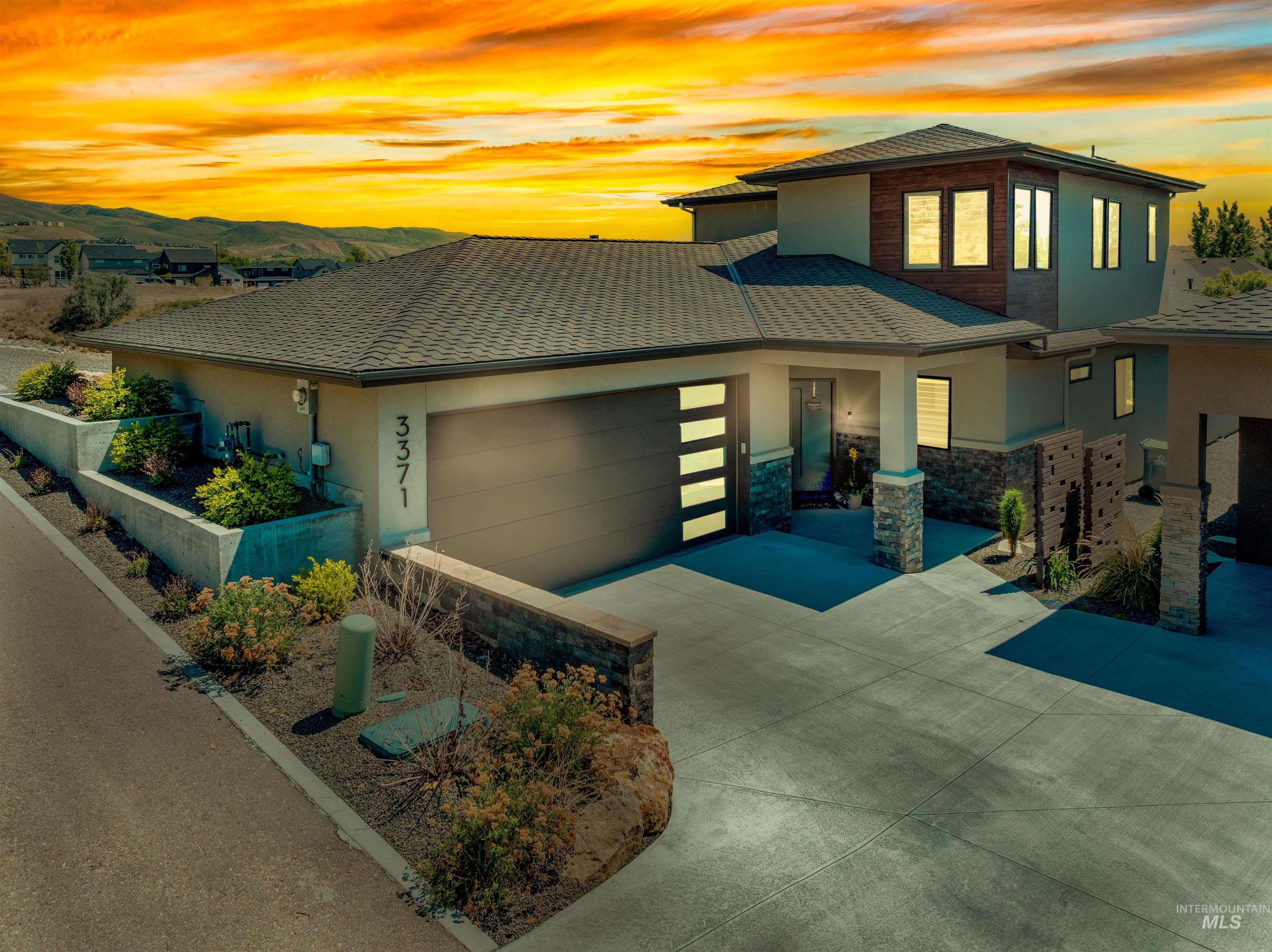 View of front of property featuring a garage, stucco siding, concrete driveway, a mountain view, and stone siding