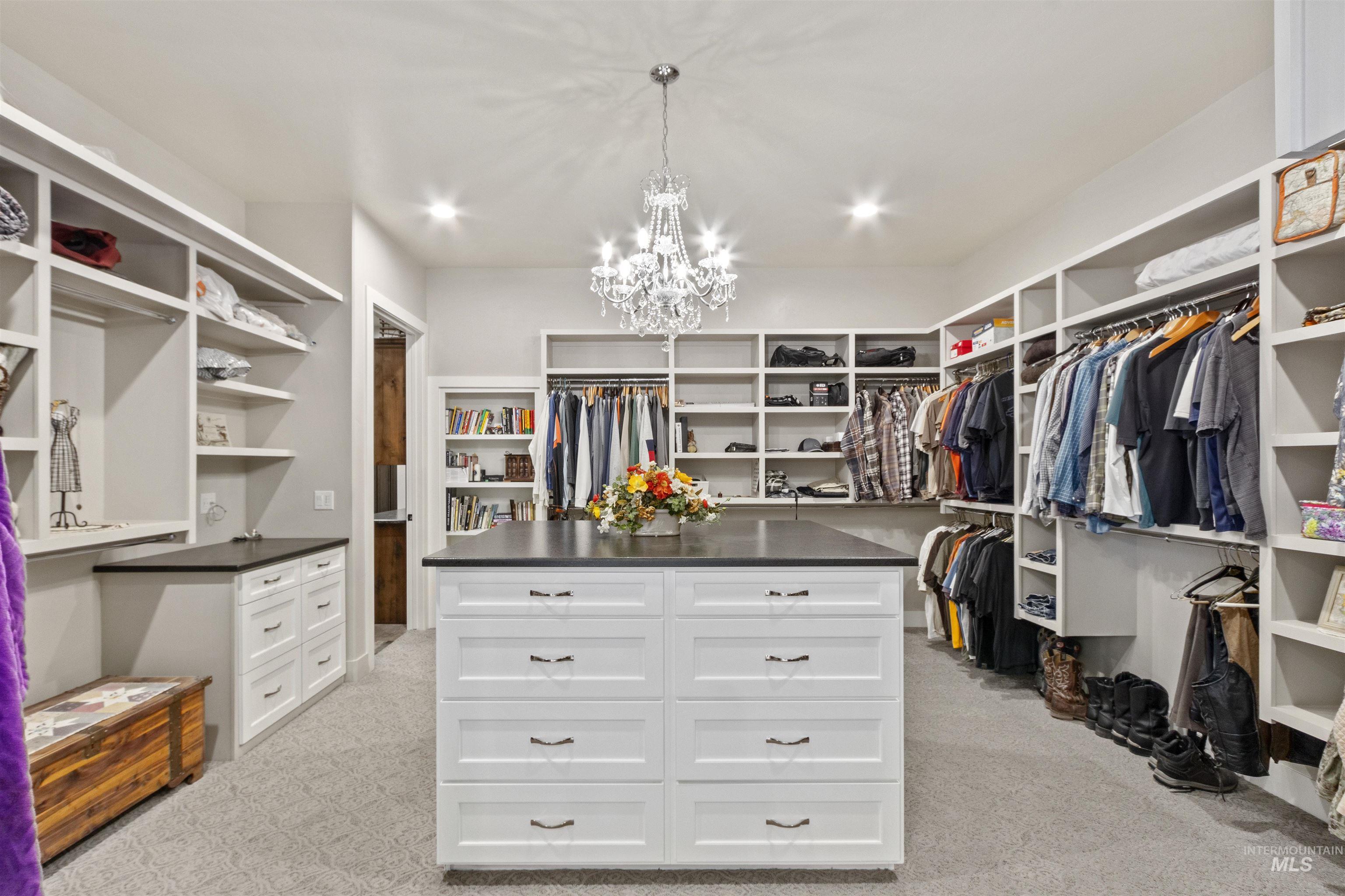Walk in closet with light carpet and a chandelier