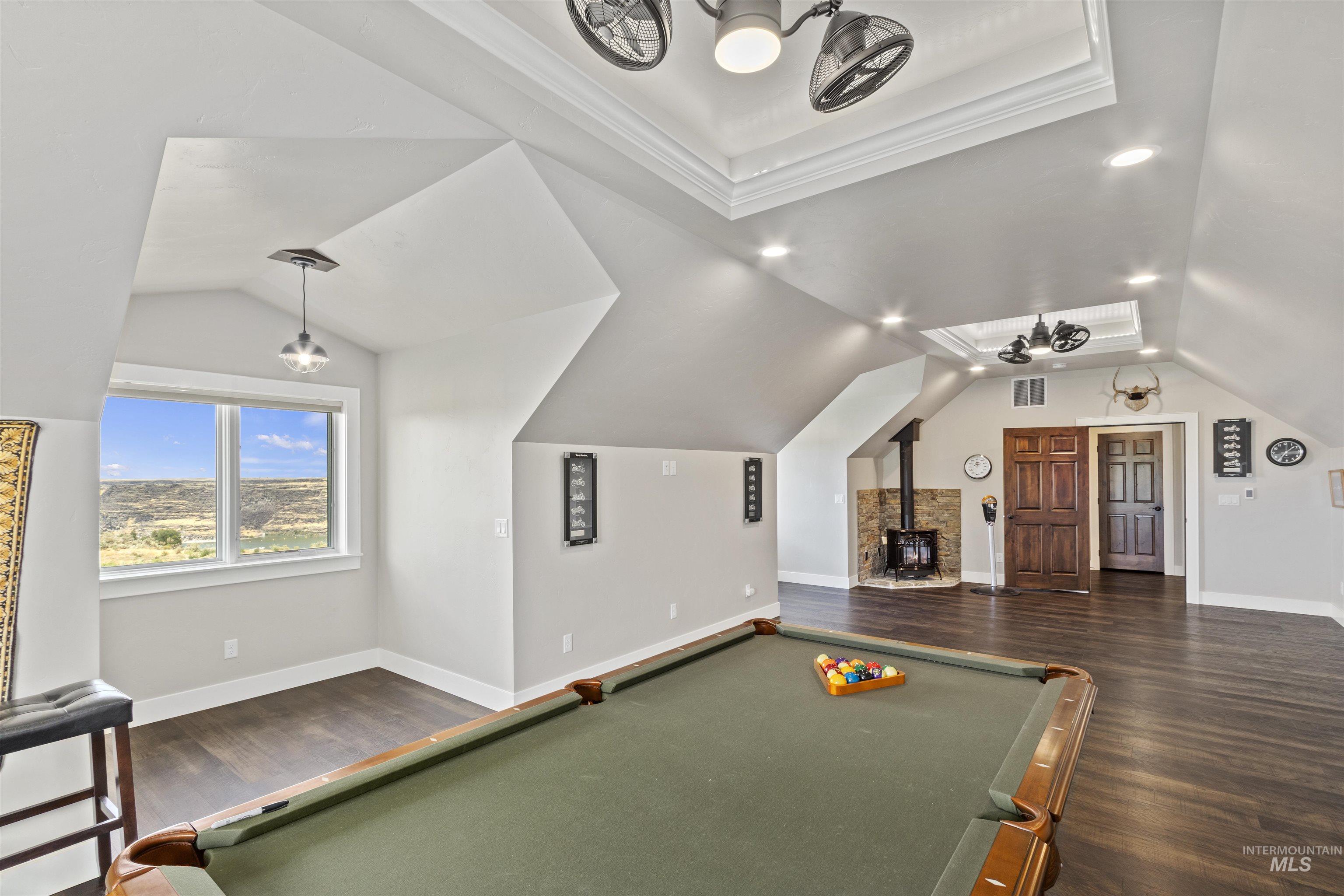Playroom with billiards, wood finished floors, a wood stove, lofted ceiling, and crown molding