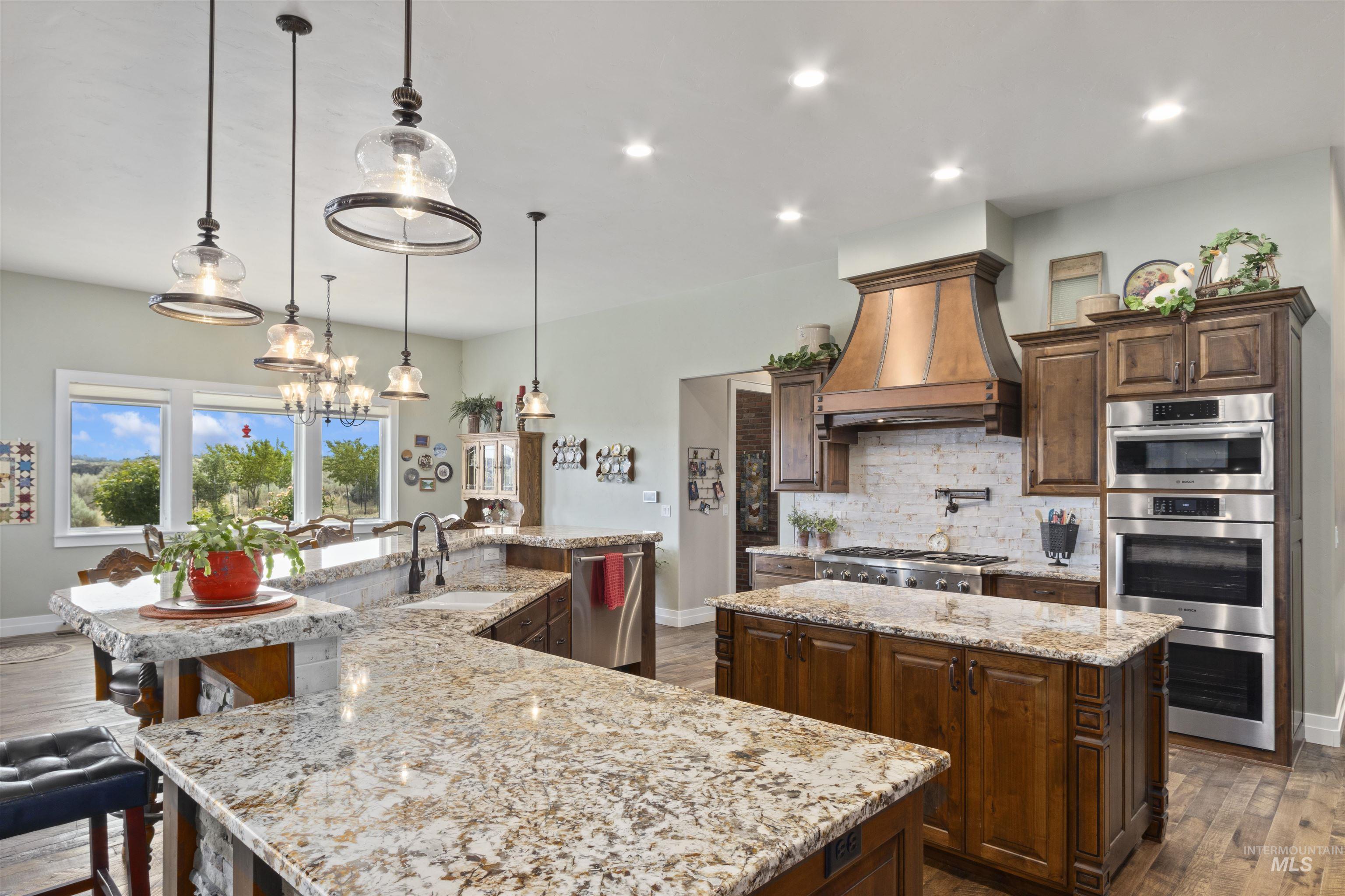 Kitchen with a large island with sink, backsplash, dark wood-style flooring, custom range hood, and recessed lighting
