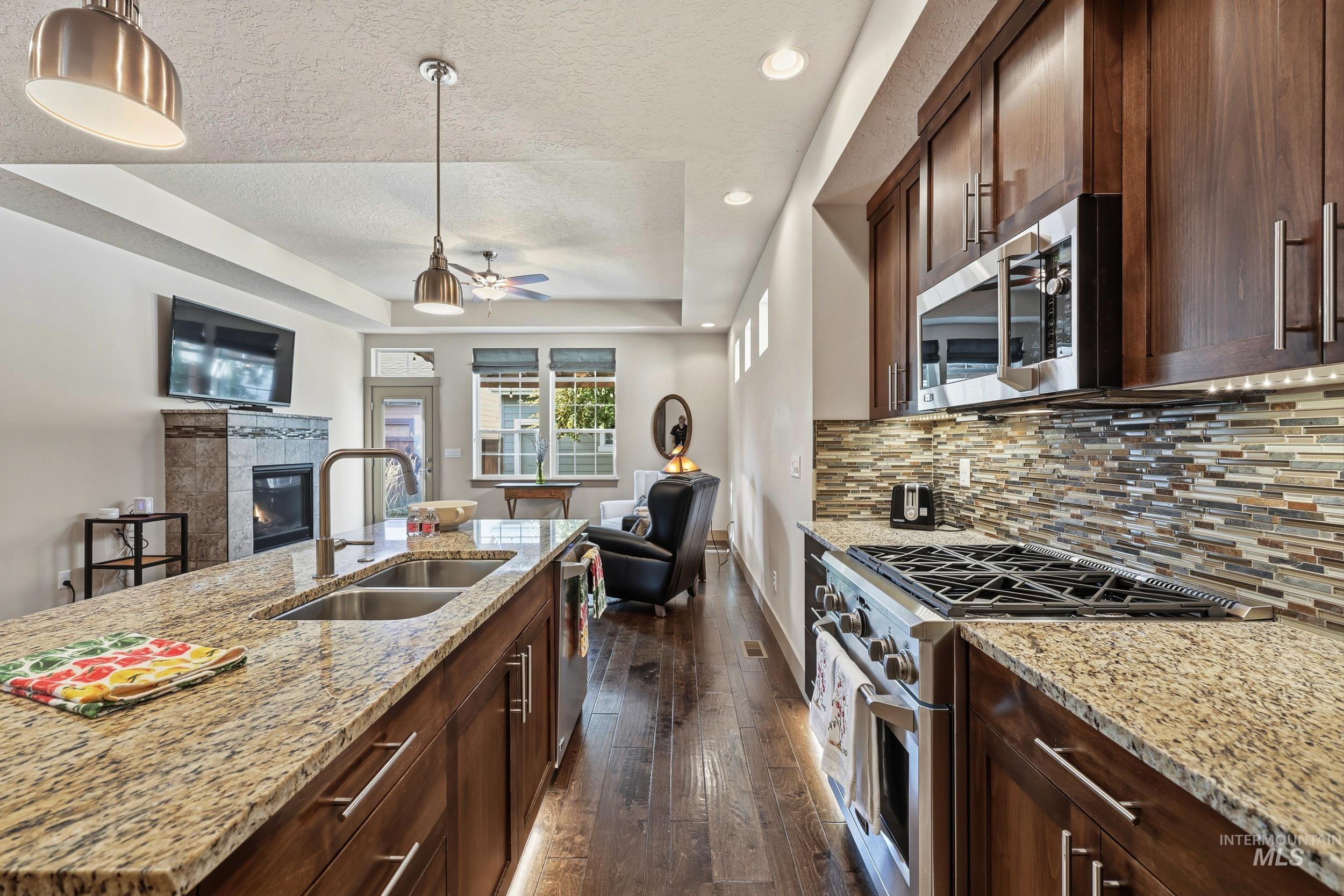 Kitchen featuring stainless steel appliances, dark brown cabinetry, a tray ceiling, recessed lighting, and a textured ceiling