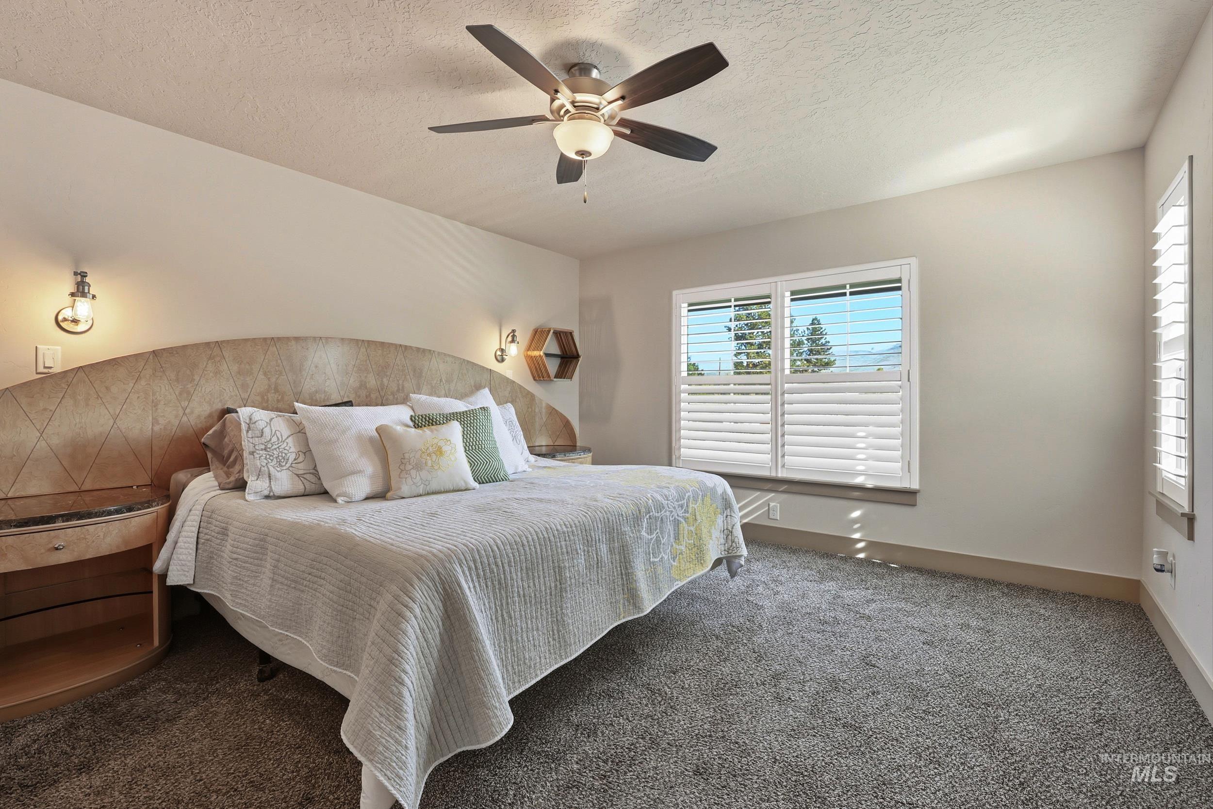 Bedroom with carpet, a textured ceiling, and a ceiling fan