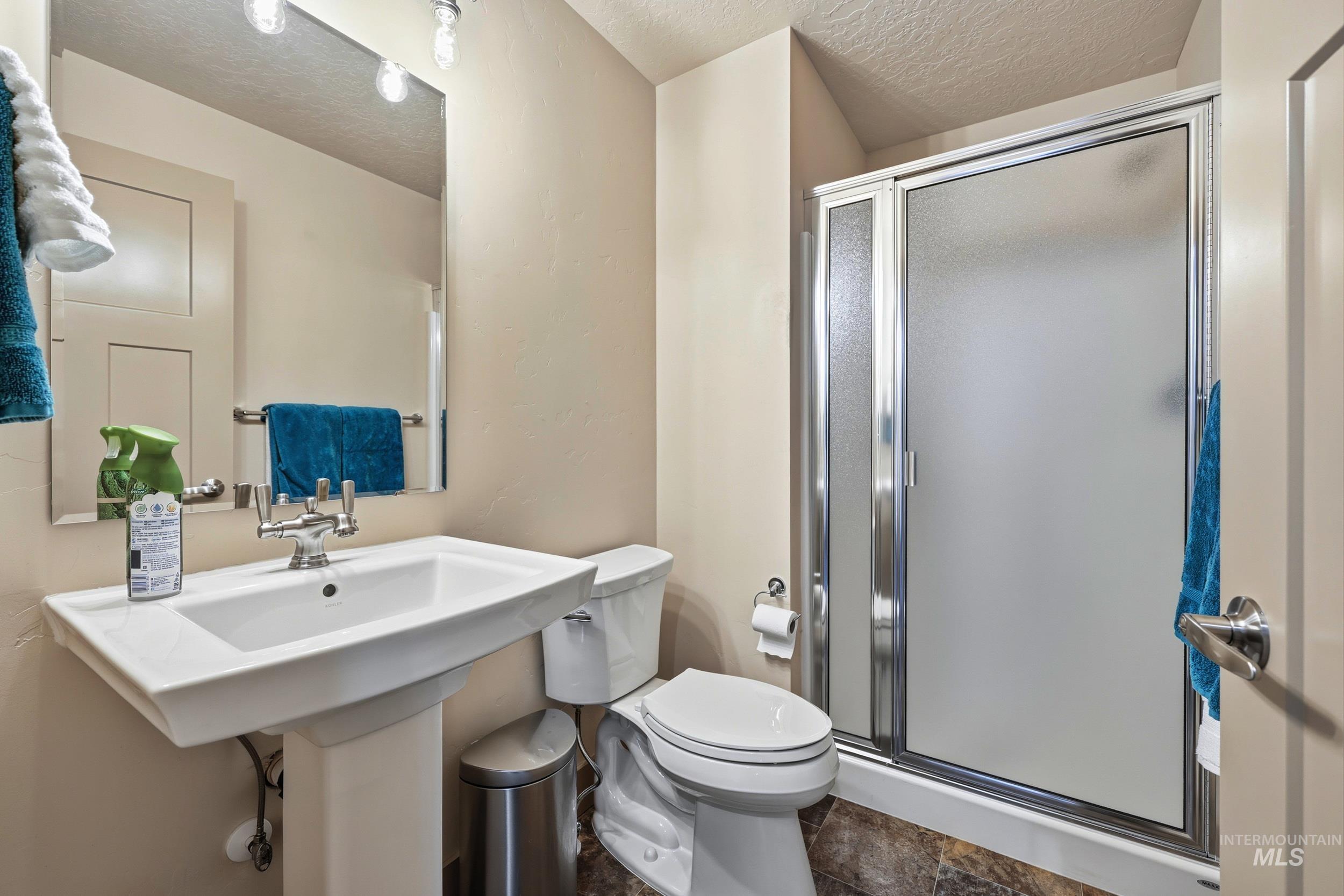 Bathroom with a stall shower and a textured ceiling