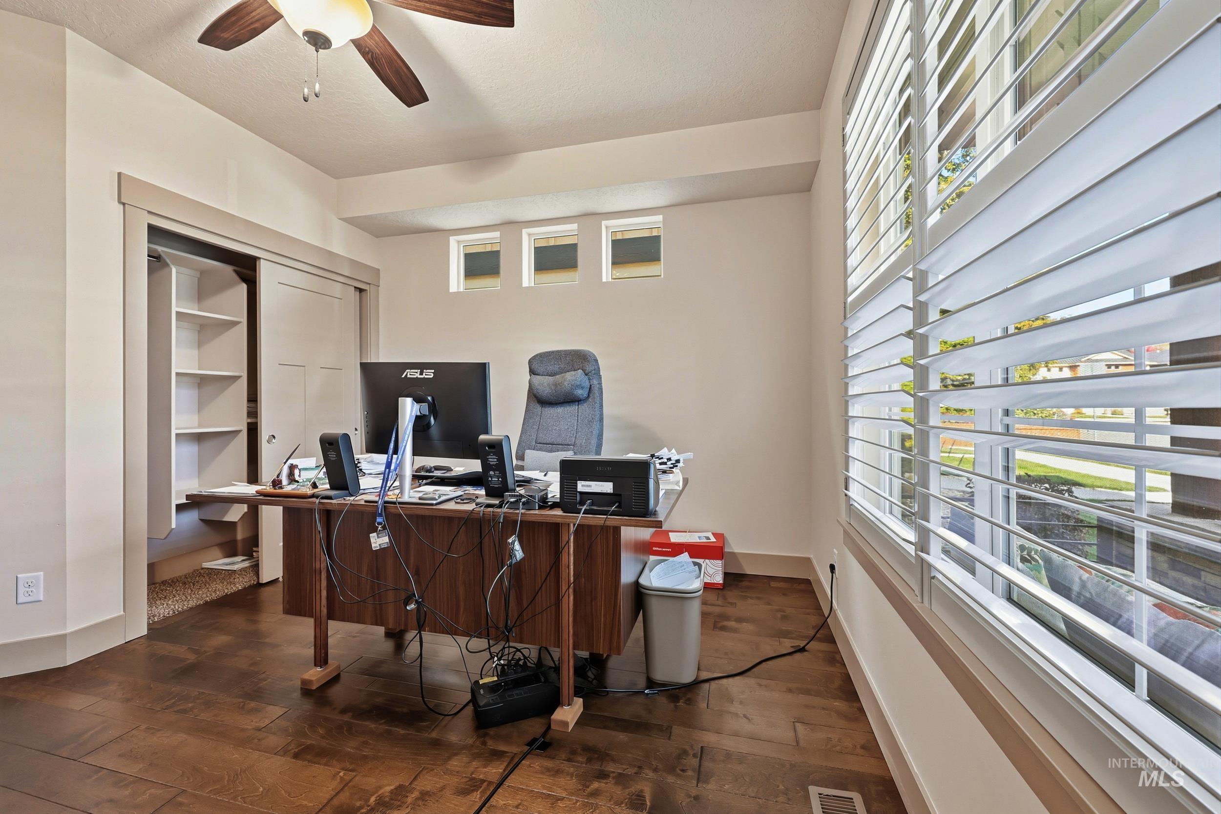 Office featuring dark wood-type flooring and ceiling fan