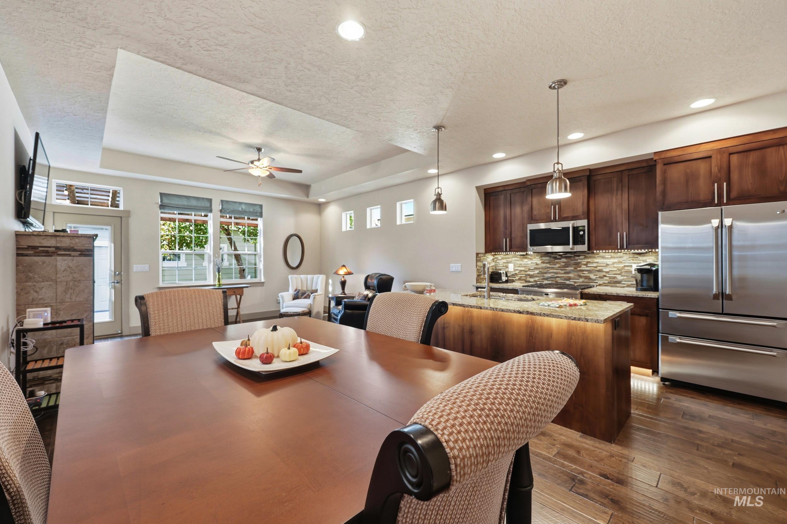 Dining room featuring a tray ceiling, a textured ceiling, a ceiling fan, dark wood-style flooring, and recessed lighting