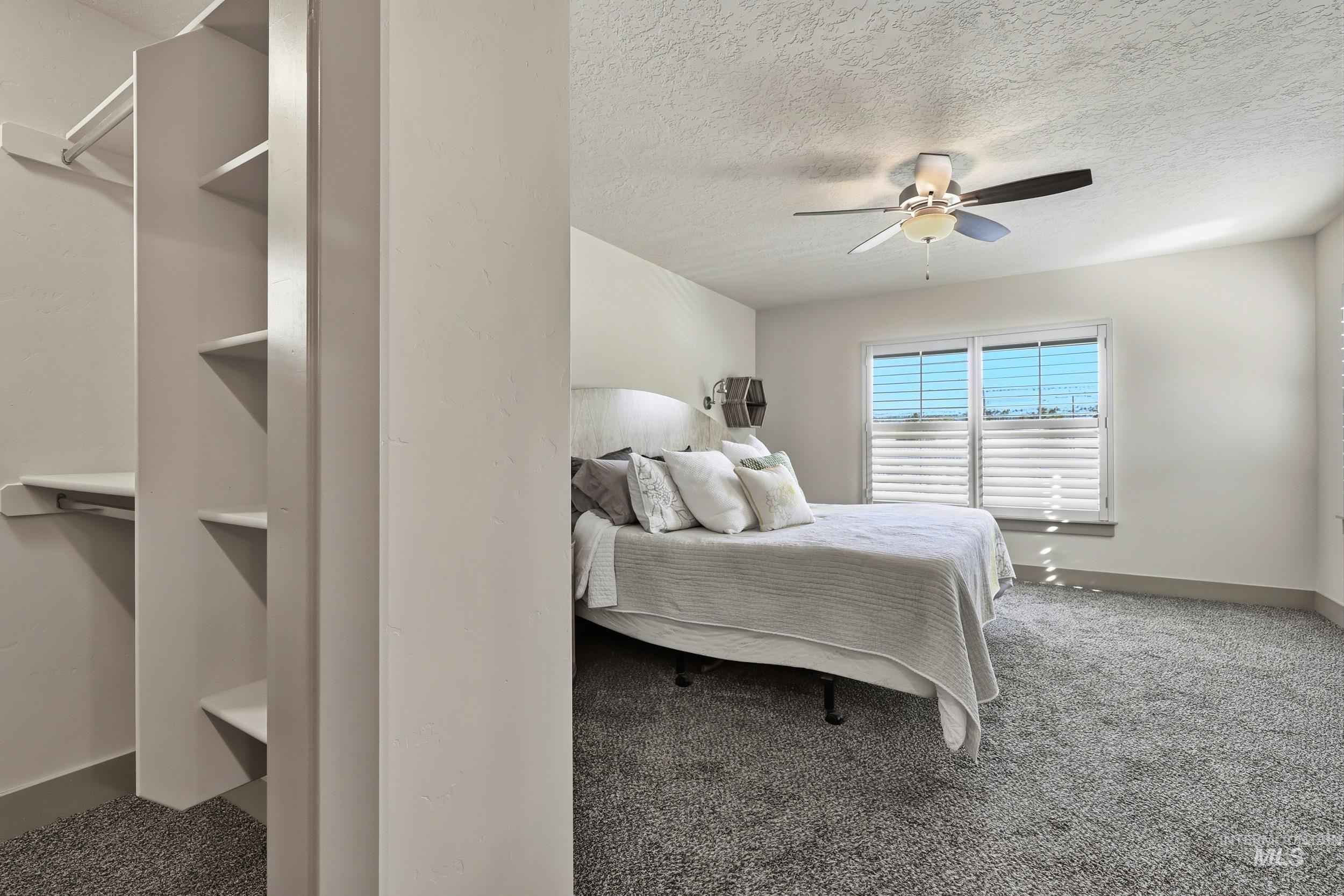 Carpeted bedroom featuring a ceiling fan and a textured ceiling