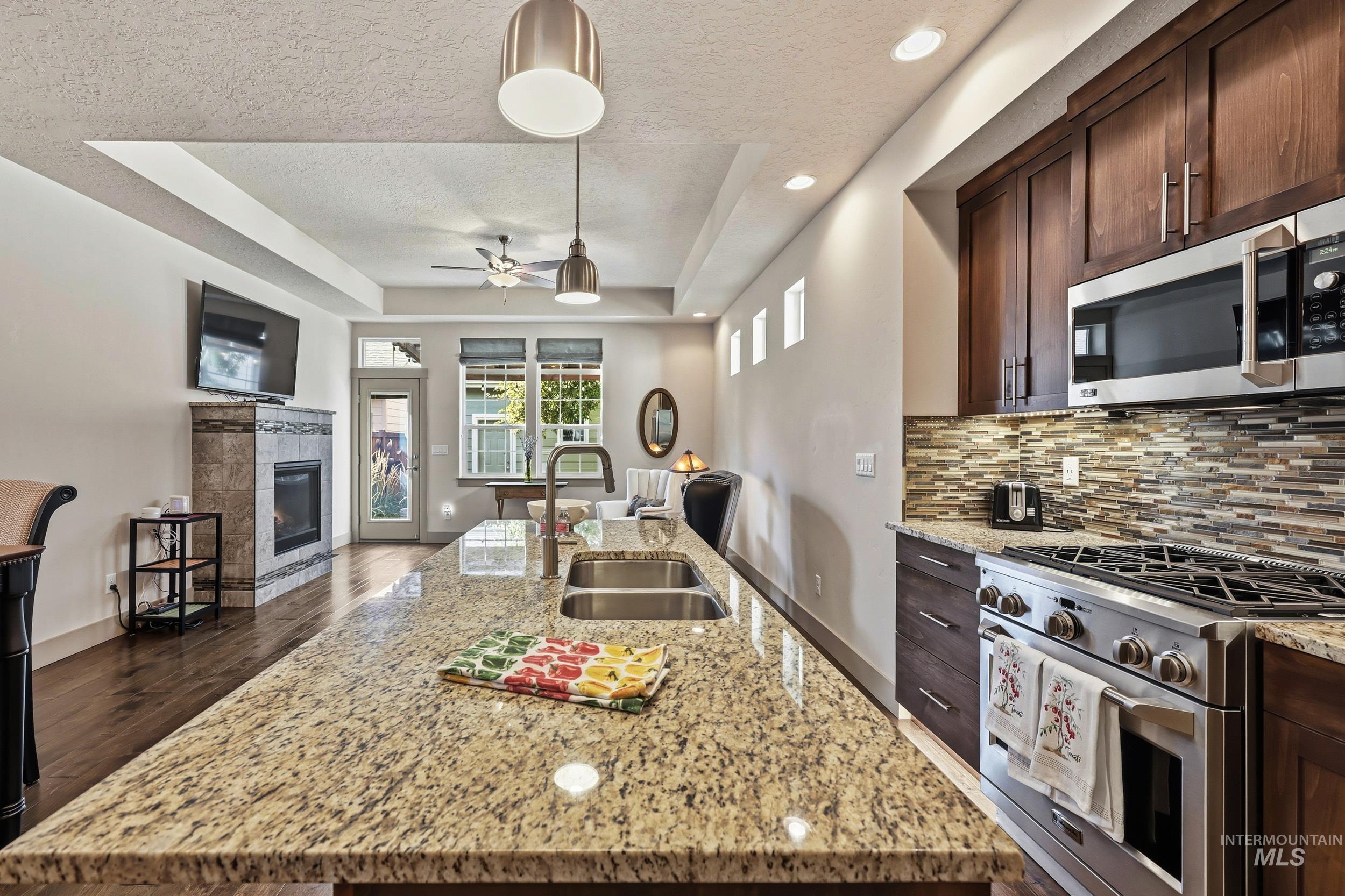 Kitchen with a raised ceiling, stainless steel appliances, open floor plan, dark brown cabinets, and recessed lighting