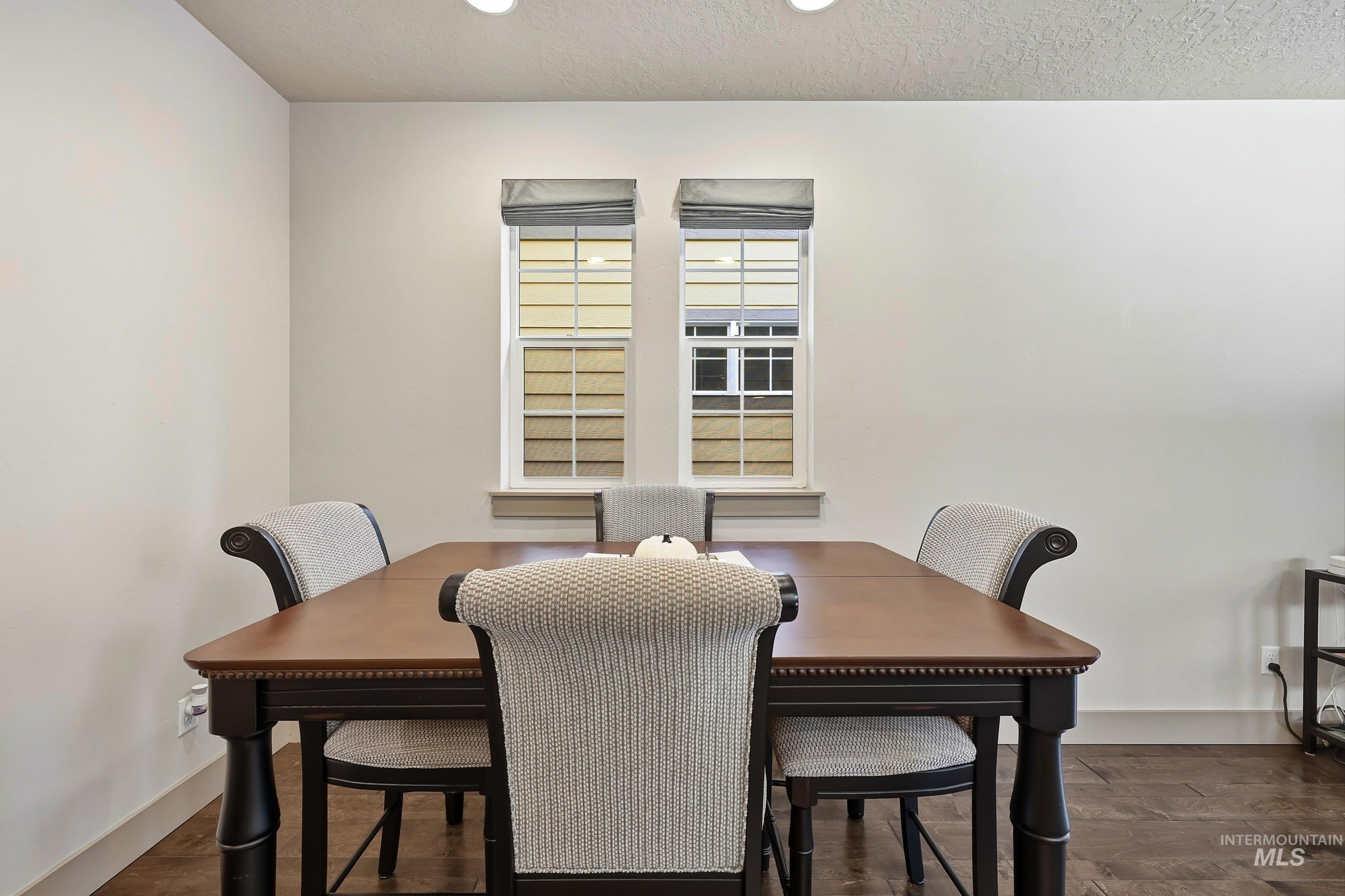 Dining area with a textured ceiling and dark wood-type flooring