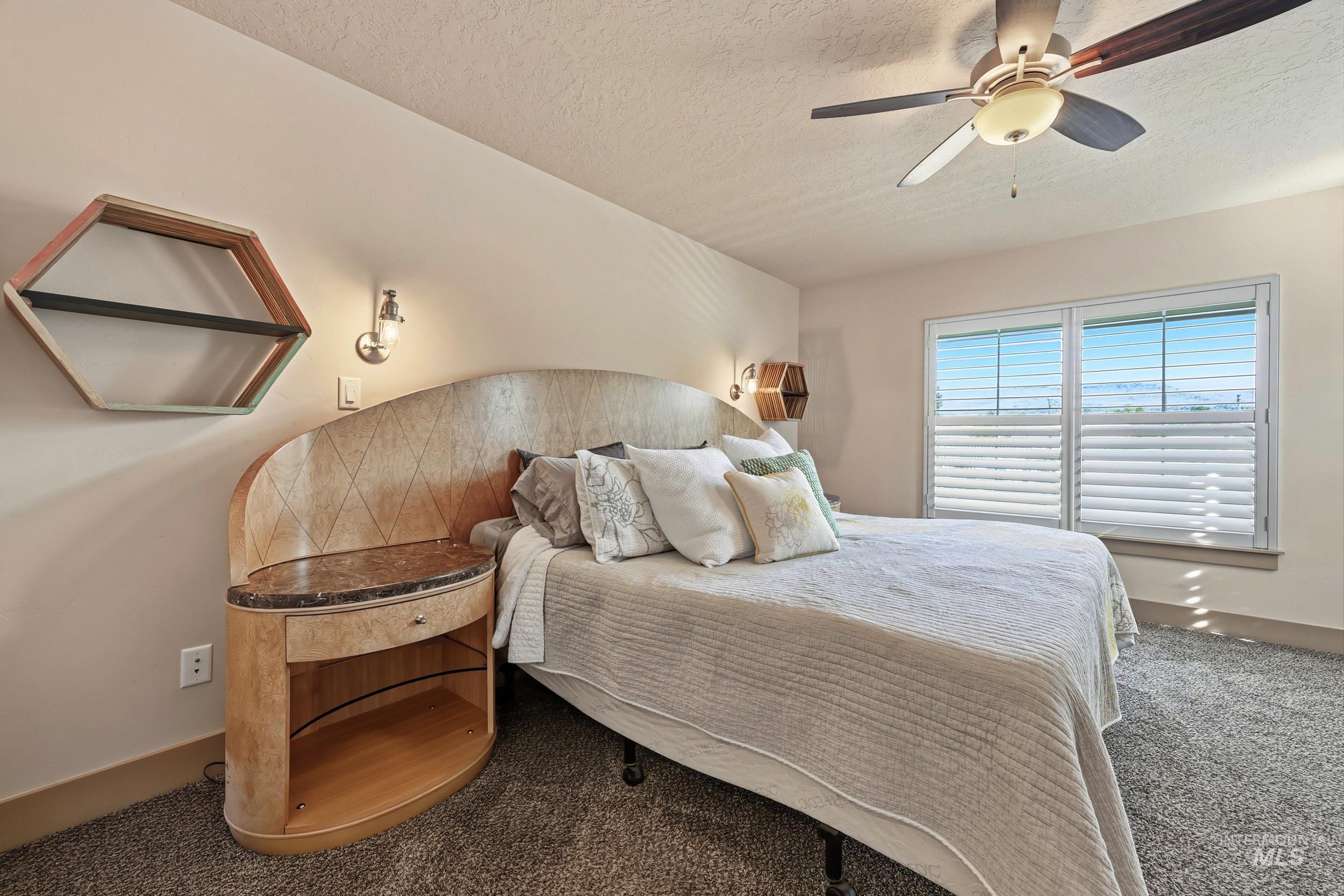 Carpeted bedroom featuring a ceiling fan and a textured ceiling