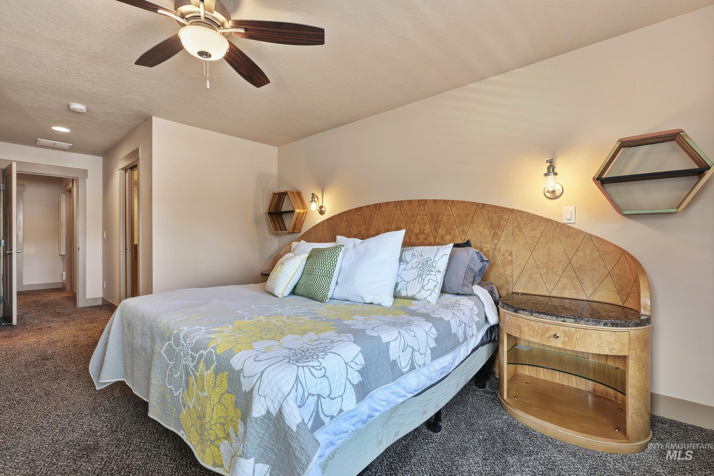 Carpeted bedroom featuring a ceiling fan and a textured ceiling