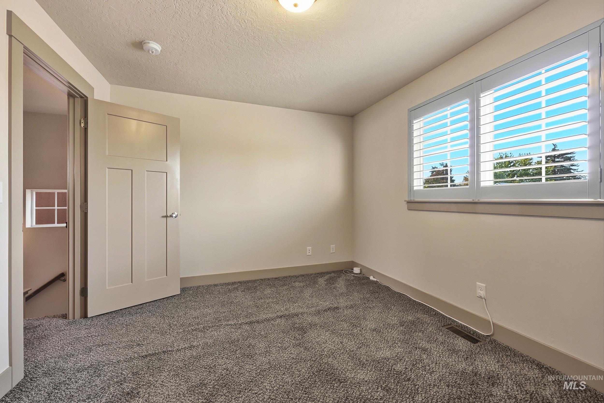 Spare room featuring carpet flooring and a textured ceiling
