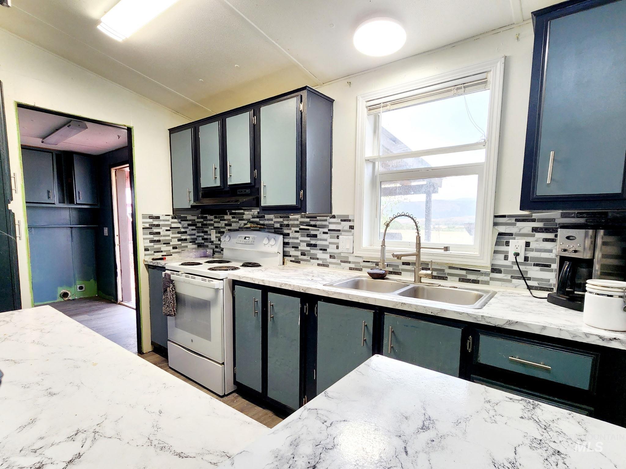 The kitchen showcases a white electric oven/range, lofted ceiling, and a decorative tiled backsplash