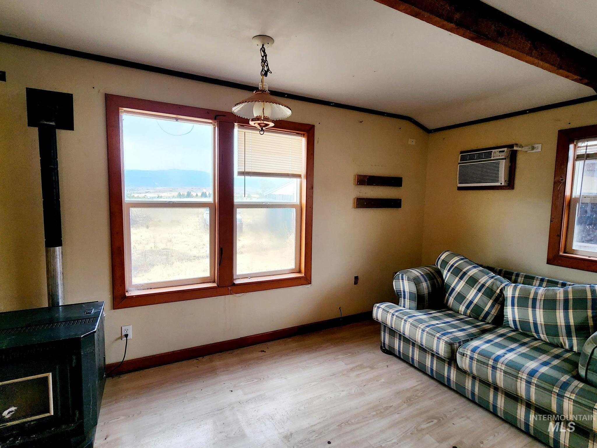Living room pellet stove, lVP floors, beam ceiling, and a wall mounted air conditioner