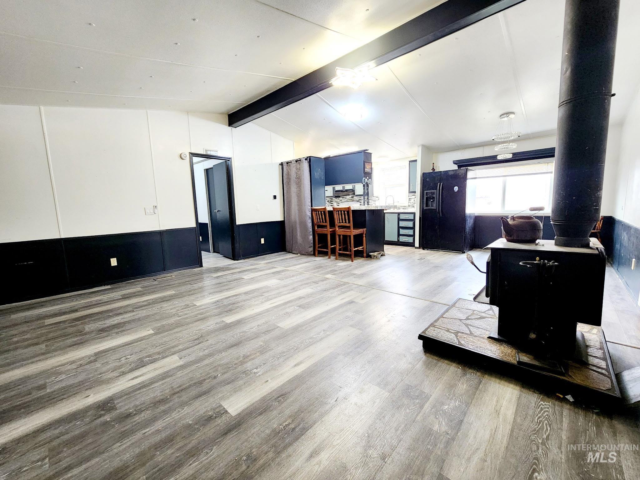 Living area, great room featuring gray colored LVP, a wood stove, and tastrfully painted wainscoting.