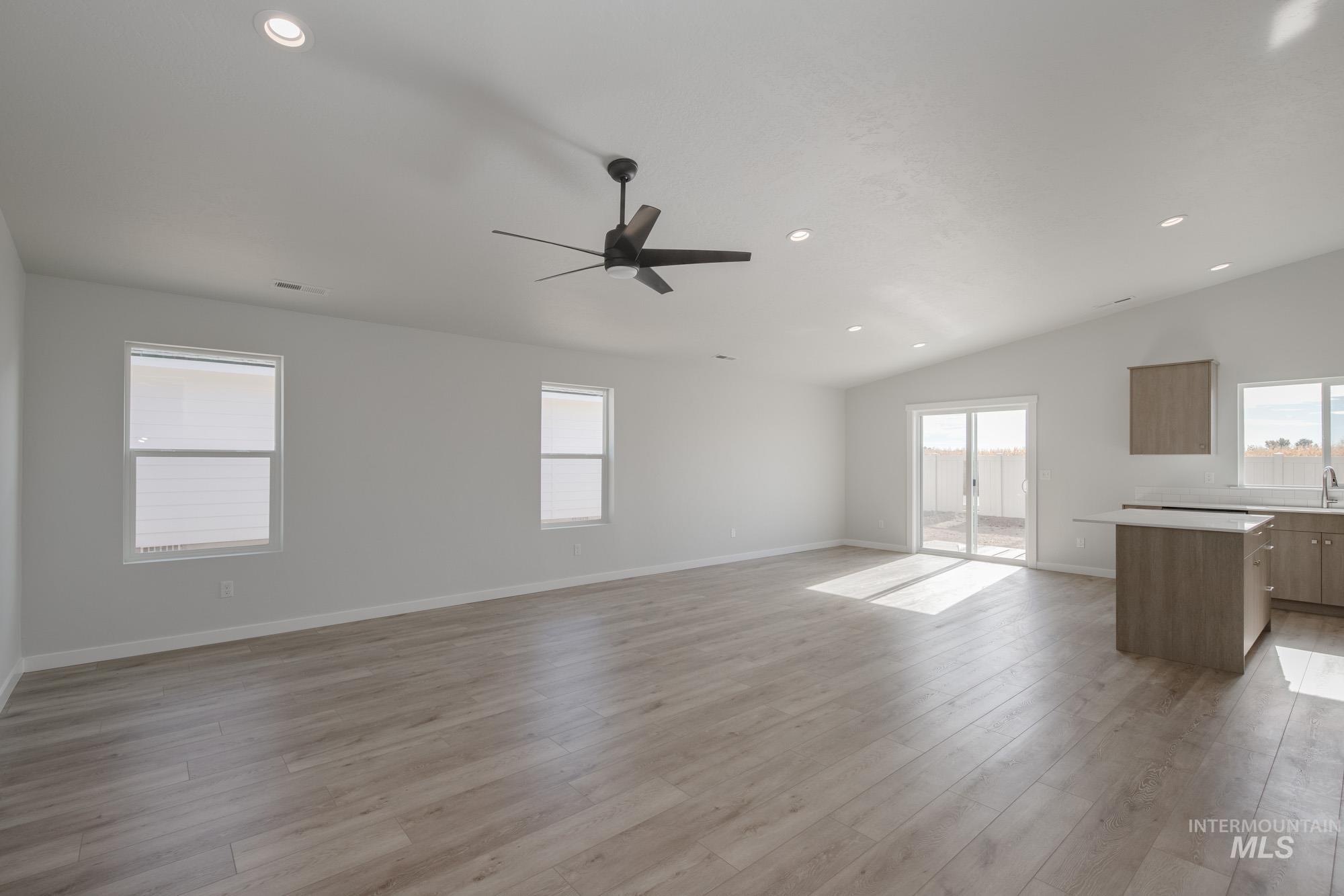 Unfurnished living room with recessed lighting, ceiling fan, light wood-type flooring, and vaulted ceiling