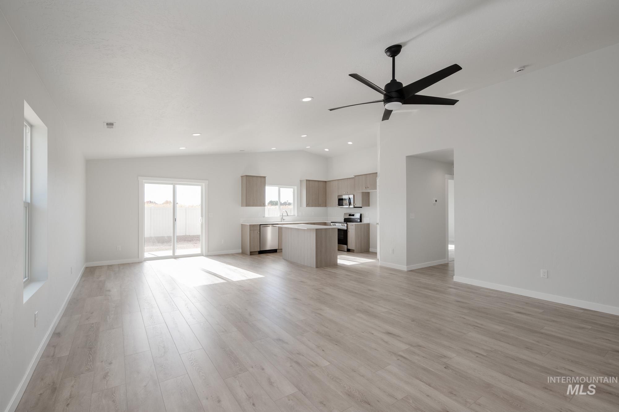 Unfurnished living room with vaulted ceiling, light wood-style floors, recessed lighting, and a ceiling fan