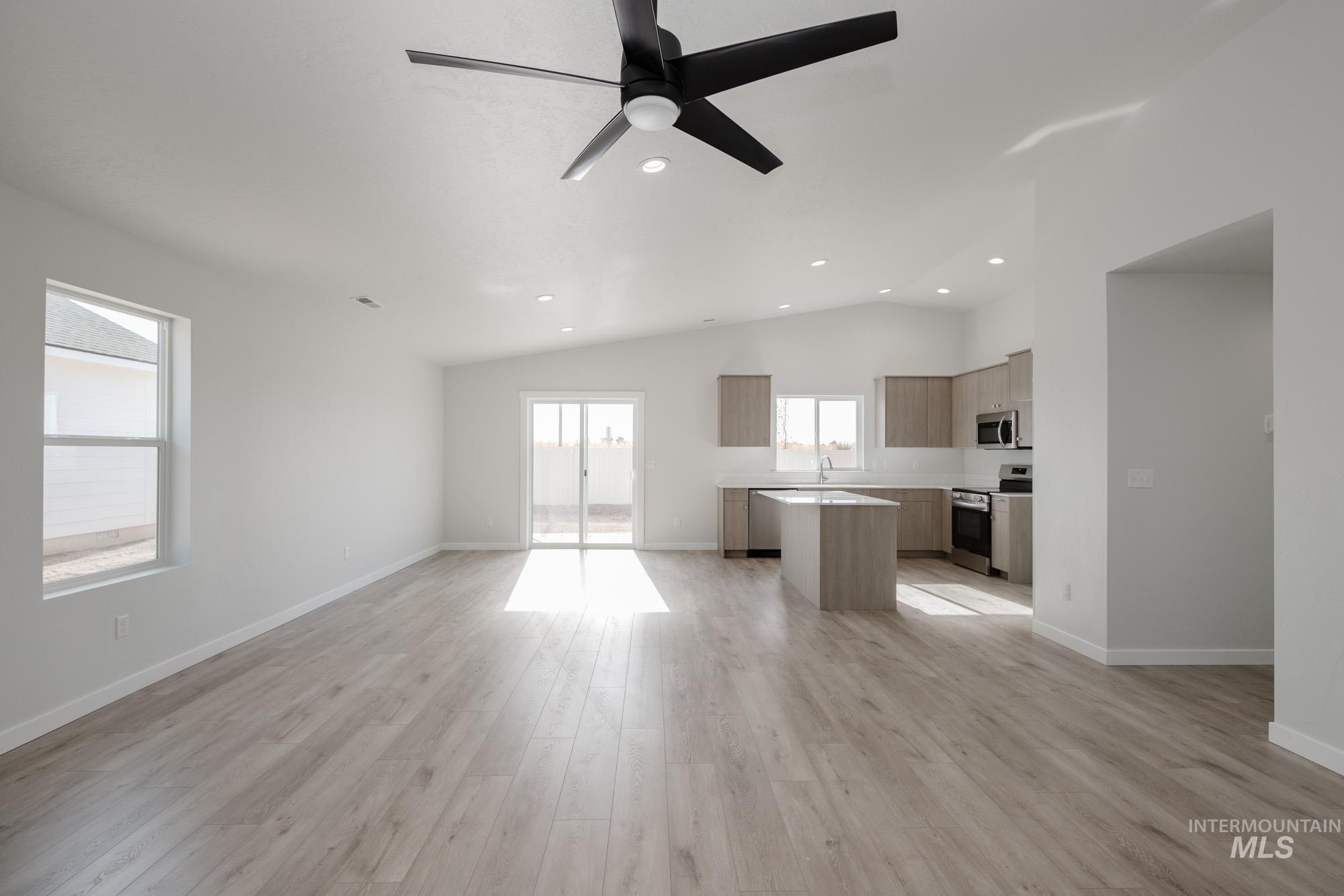 Unfurnished living room with light wood-style floors, ceiling fan, vaulted ceiling, and recessed lighting